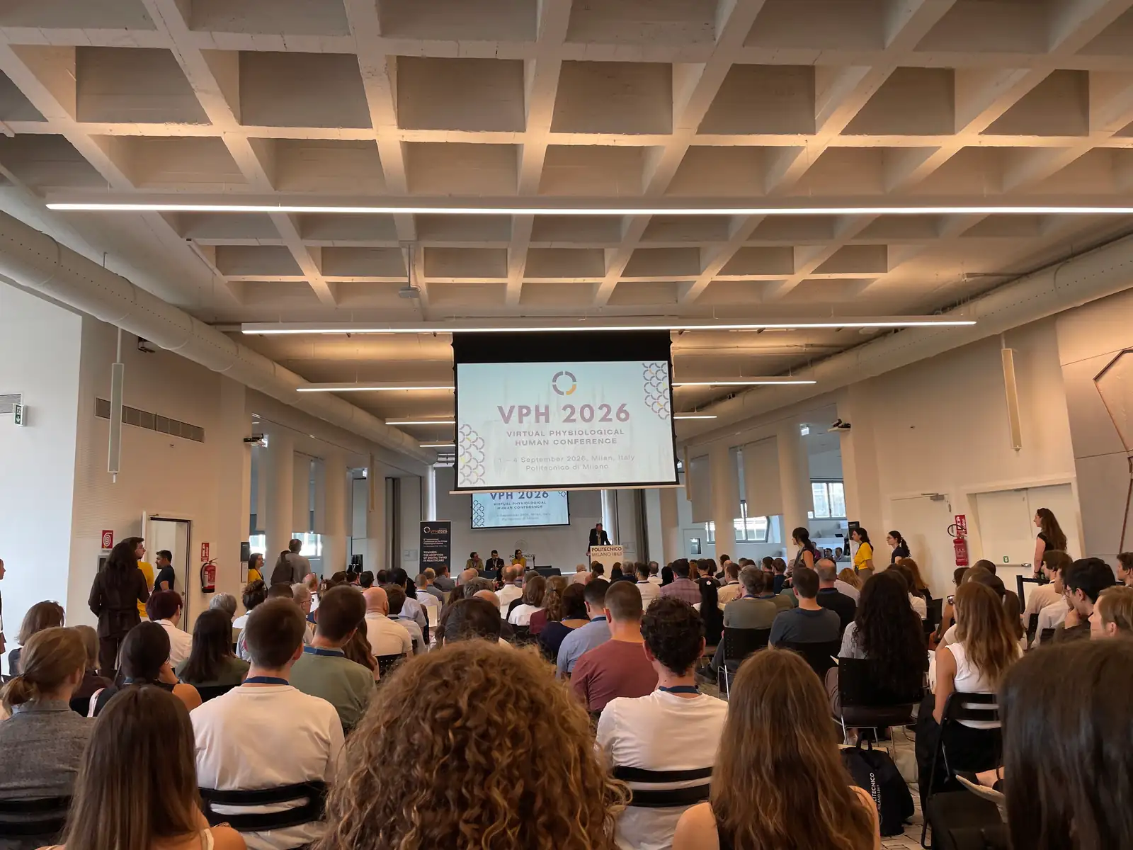 Full plenary hall at VPH 2026 in Milan, with the audience facing a large screen showing the conference logo.